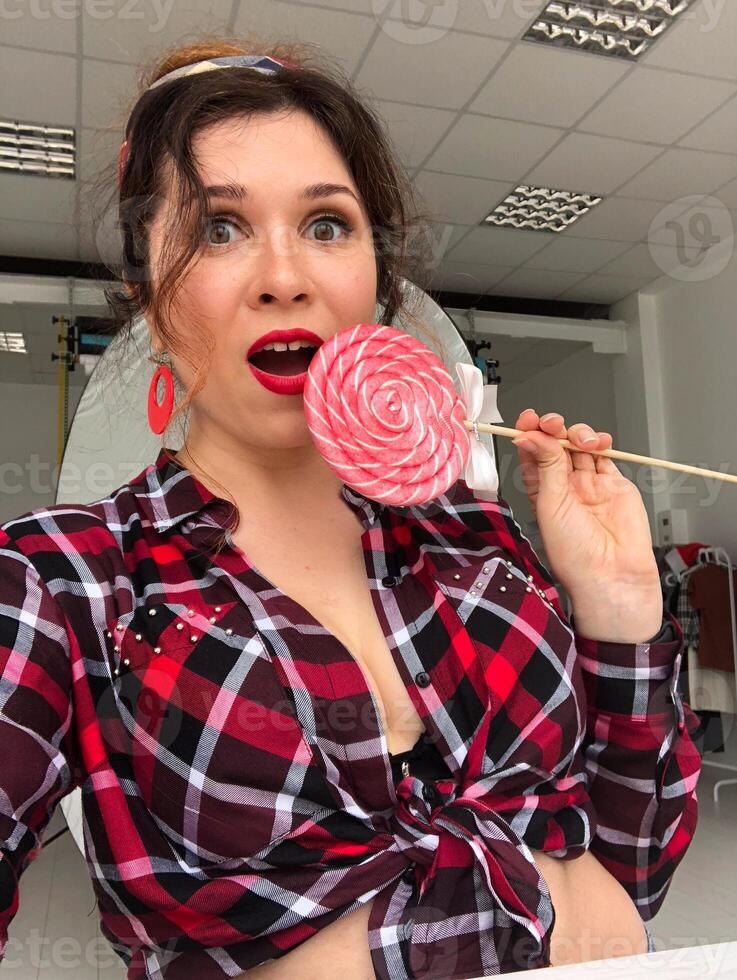 Young woman in retro pinup vibes with a sweet twist lollipop. Playfulness, retro charm and vintage aesthetic photo