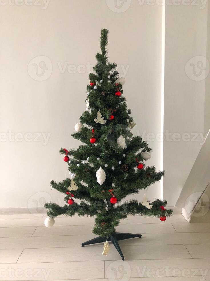 A minimalist Christmas tree decorating a modern living space, adorned with red, white, and silver ornaments. Simplicity design and festive charm to the clean, contemporary room. photo
