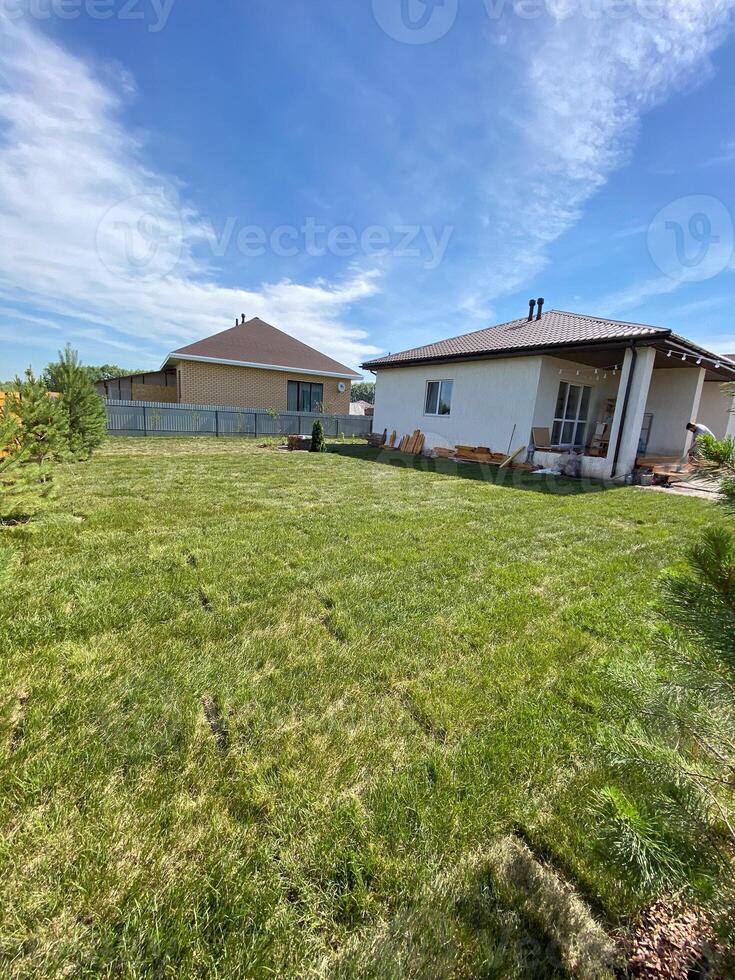 Newly laid lawn sen in the back garden of a large detached house. A newly built village house in front of the lawn. photo