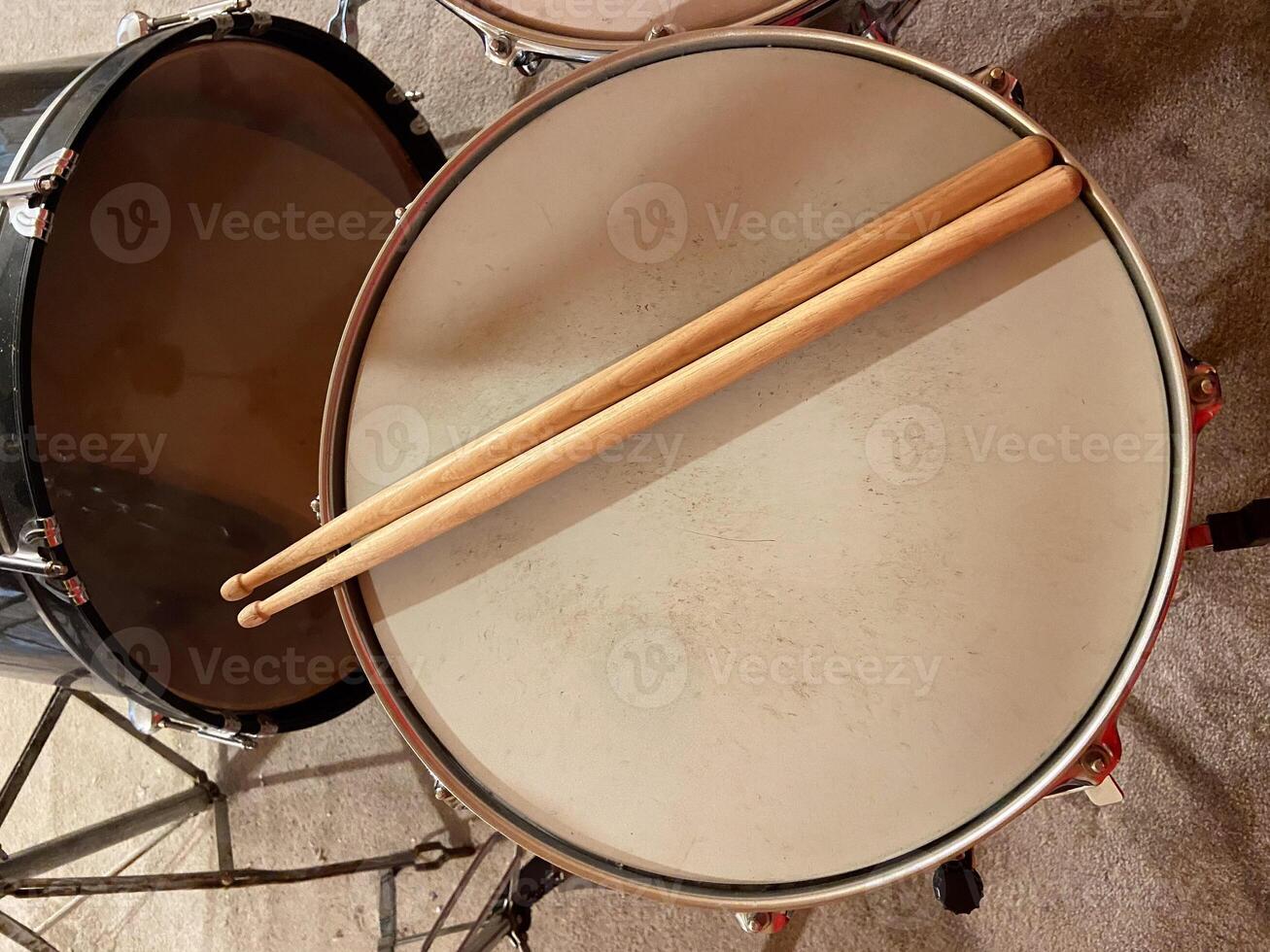 Pair of wooden drumsticks rests on a snare drum, inviting rhythm and energy. Musical experience waiting to unfold in this intimate setting photo