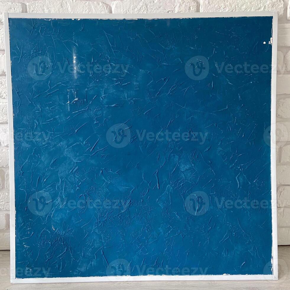 Textured deep blue panel is set against a white brick wall, emphasizing its rich color and intricate surface patterns. This composition reflects a perfect blend of modern art and minimalistic design photo
