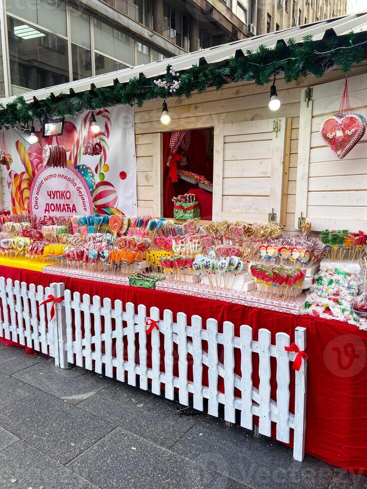 Colorful heart-shaped cookies hang elegantly on display at a festive Christmas market stall. Vibrant array of sweets. Inviting and cheerful atmosphere winter holidays. photo