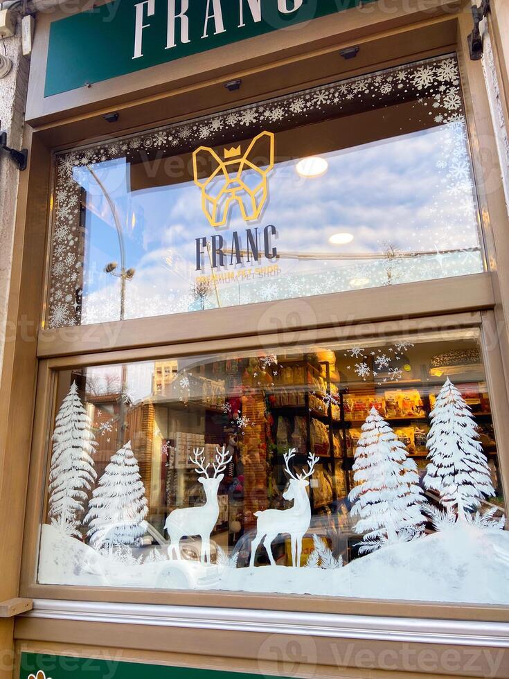 Frosted ornaments delicately decorate a window, showcasing hand-painted Christmas winter scenes with snowy landscapes and cozy cabins. Designs reflect festive spirit and charm of winter holiday season photo