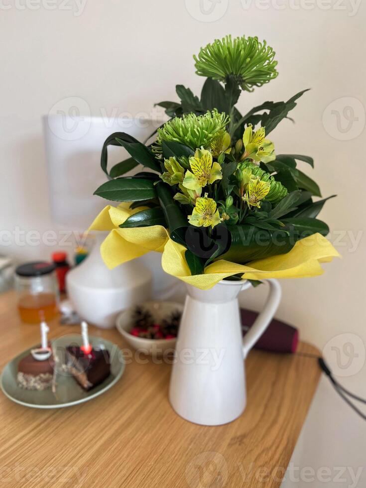 Elegant yellow and green floral arrangement in white vase on table. Birthday concept photo