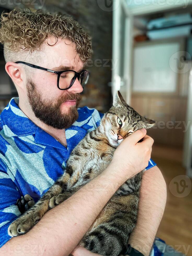 Warm moment between a millennial man and his cat, bond and affection shared in a cozy home environment. Portrait at home. Pet and friendship concept photo