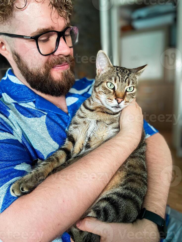 Warm moment between a millennial man and his cat, bond and affection shared in a cozy home environment. Portrait at home. Pet and friendship concept photo
