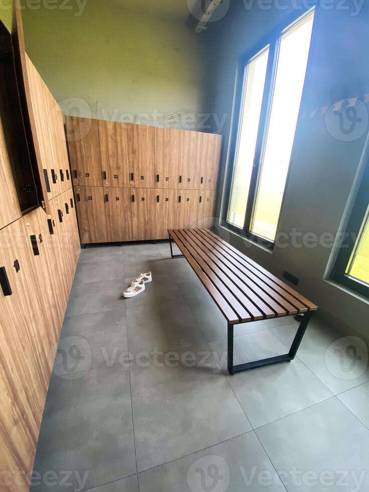 Wooden bench in empty locker room at gym photo