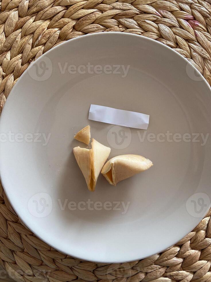 Broken fortune cookie with a blank paper slip on a gray background. Moment of anticipation and mystery that accompanies the opening of a fortune cookie photo