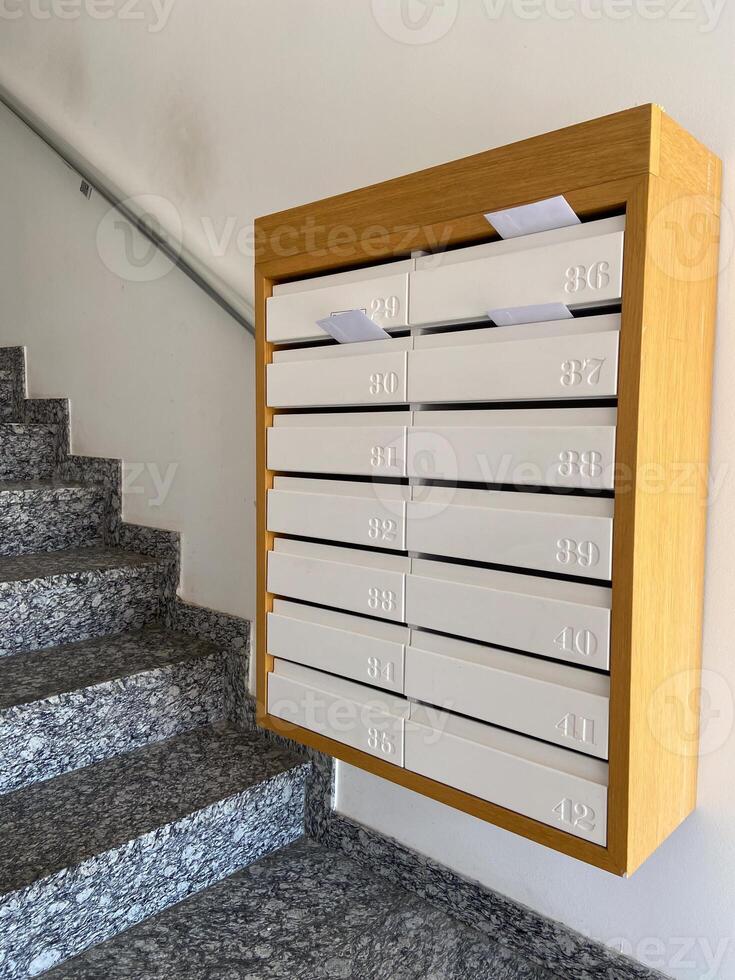 Row of mailboxes in a modern apartment building, with letters sticking out, symbolizing communication and daily life. Blend of functionality and design, capturing the essence of urban living photo