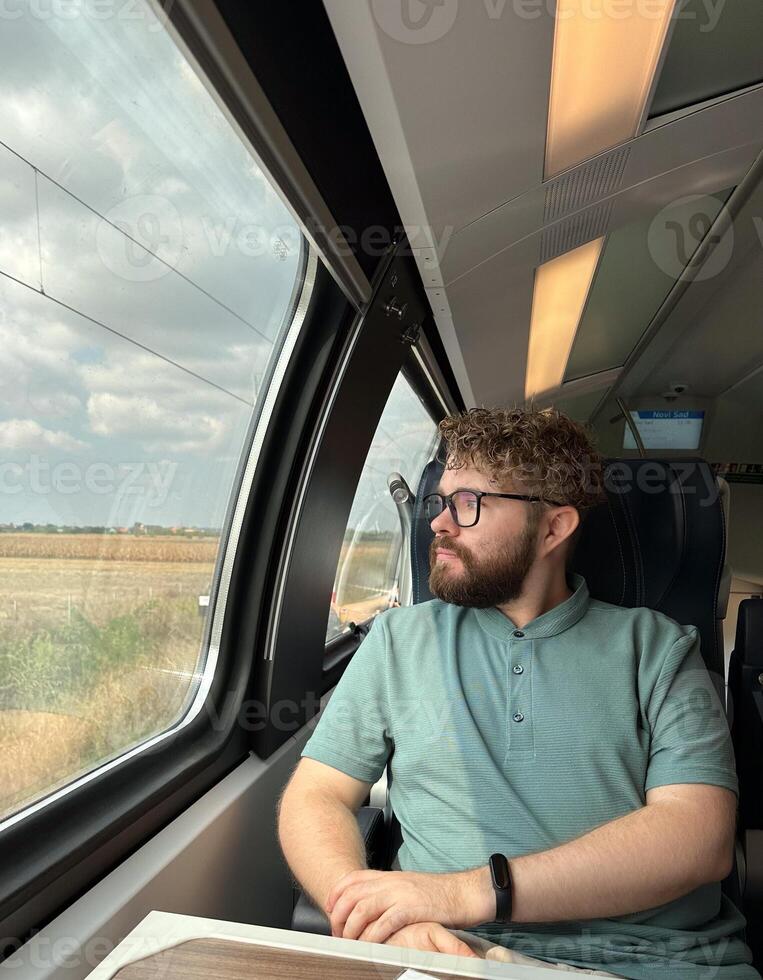 Man traveler enjoying a serene view from a train window. Calm and reflection during a peaceful journey photo