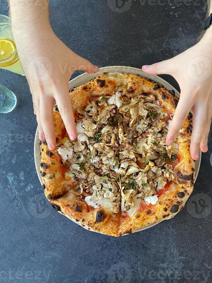 Hands taking slices of freshly baked pizza with chicken and herbs on a dark table. Enjoying a gourmet pizza, emphasizing appetizing toppings and rustic crust photo