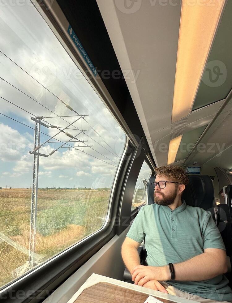 Man traveler enjoying a serene view from a train window. Calm and reflection during a peaceful journey photo