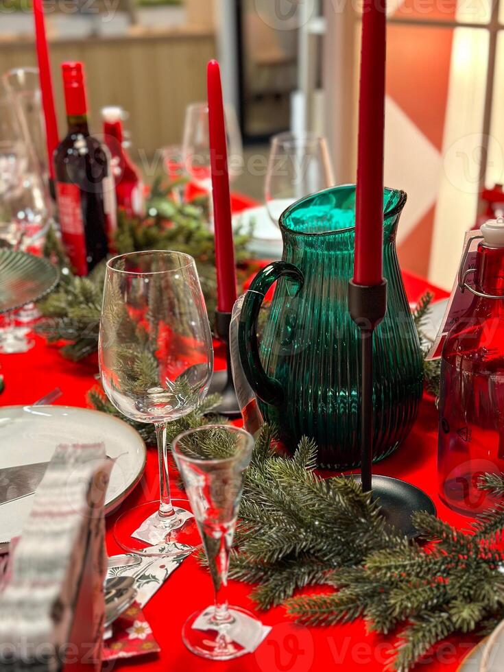 Christmas set table is adorned with festive decorations, ready for a joyful winter holiday gathering. Vibrant red tablecloth and elegant tableware create a warm and inviting atmosphere photo