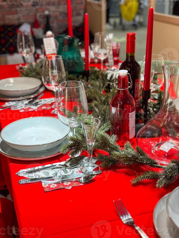 Christmas set table is adorned with festive decorations, ready for a joyful winter holiday gathering. Vibrant red tablecloth and elegant tableware create a warm and inviting atmosphere photo