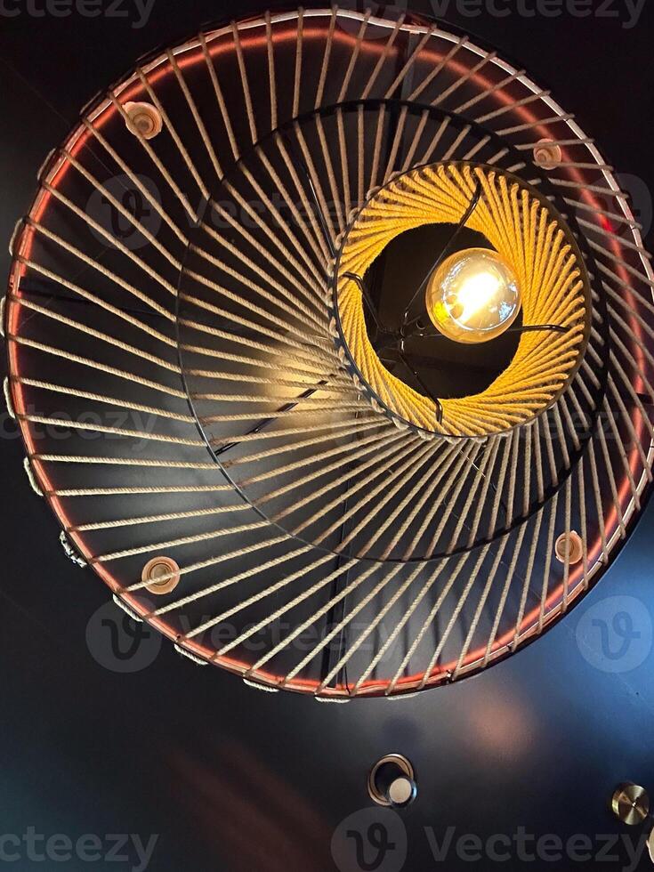 An artistic ceiling light fixture with intricate rope design, lamp. Warm, glowing bulb creates a cozy ambiance and striking visual effect photo