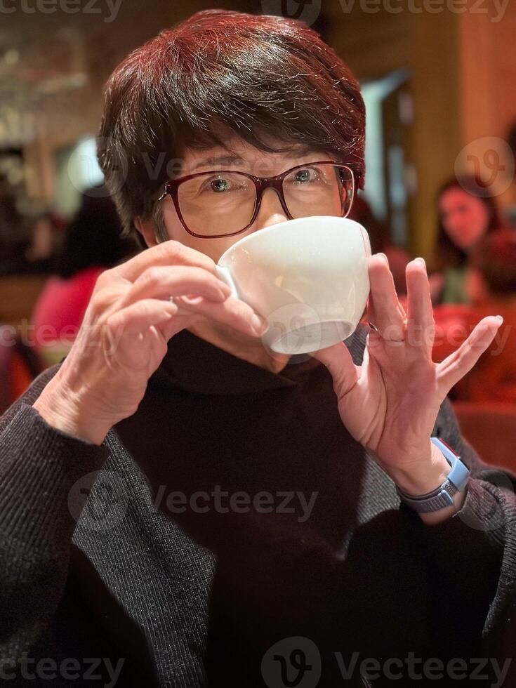 Woman enjoying a warm drink in a cozy cafe. Savoring the moment with quiet reflection and comfort. Break and free time concept photo