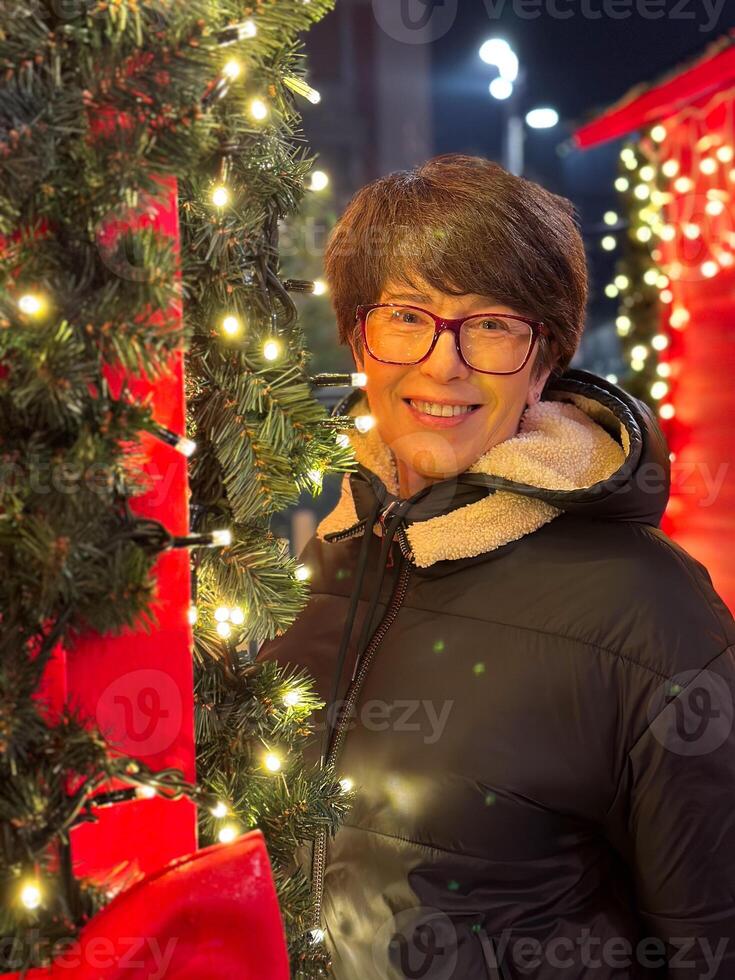 Cheerful woman poses amidst festive lights and decorations, capturing the warmth and joy of holiday Christmas season. Surrounding glowing elements photo