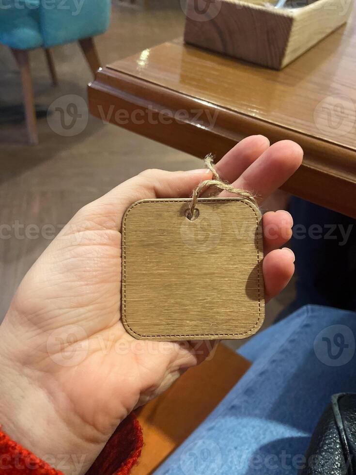 Close-up hand holds a small wooden tag with a twine loop. Copy space and empty place for text. Natural texture and simplicity of the tag create a connection to artisanal craftsmanship photo