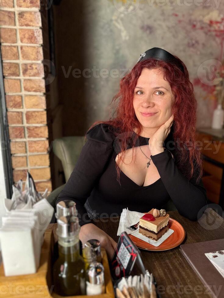 Millennial woman with red hair sits thoughtfully at a rustic cafe table, surrounded by a cozy and artistic atmosphere. Soft lighting and her pensive expression photo