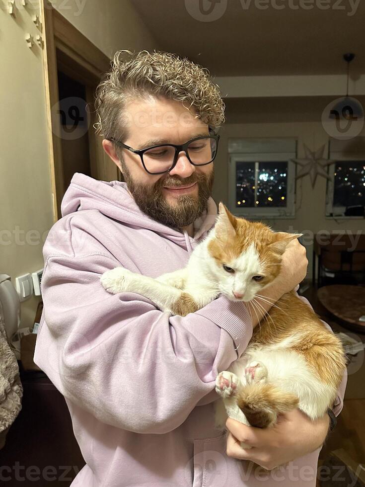 Warm moment between a millennial man and his cat, bond and affection shared in a cozy home environment. The background features a christmas decor at home. Pet and friendship concept photo