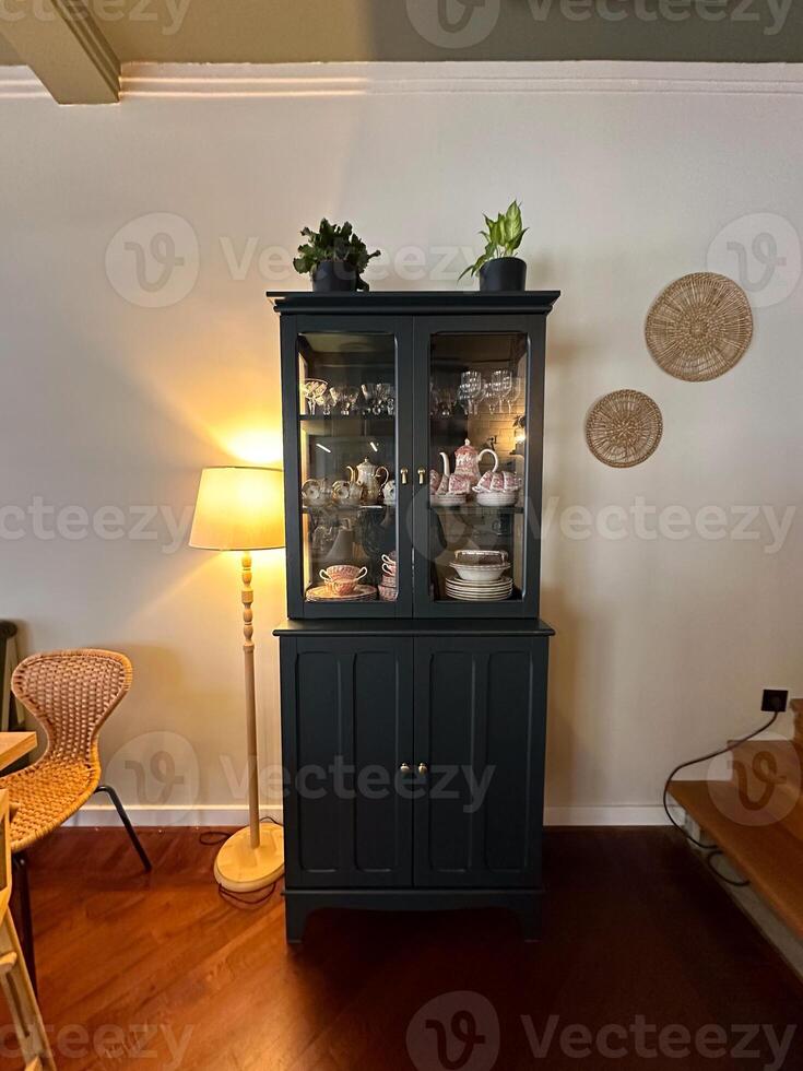 Classic wooden cabinet stands elegantly in a cozy room, displaying exquisite china and adorned with potted plants. warm lighting photo