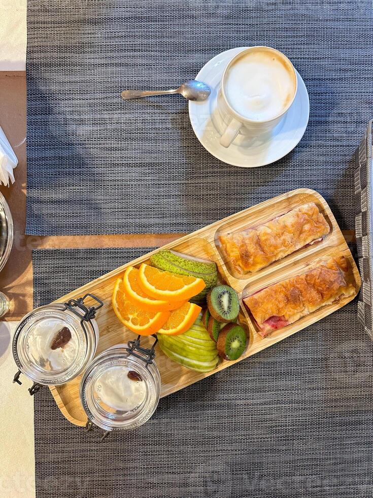 colorful breakfast spread showcases sliced fruits and pastries on a wooden tray, offering a vibrant start to the day. accompanied by glasses of water, this arrangement exudes freshness and simplicity. photo