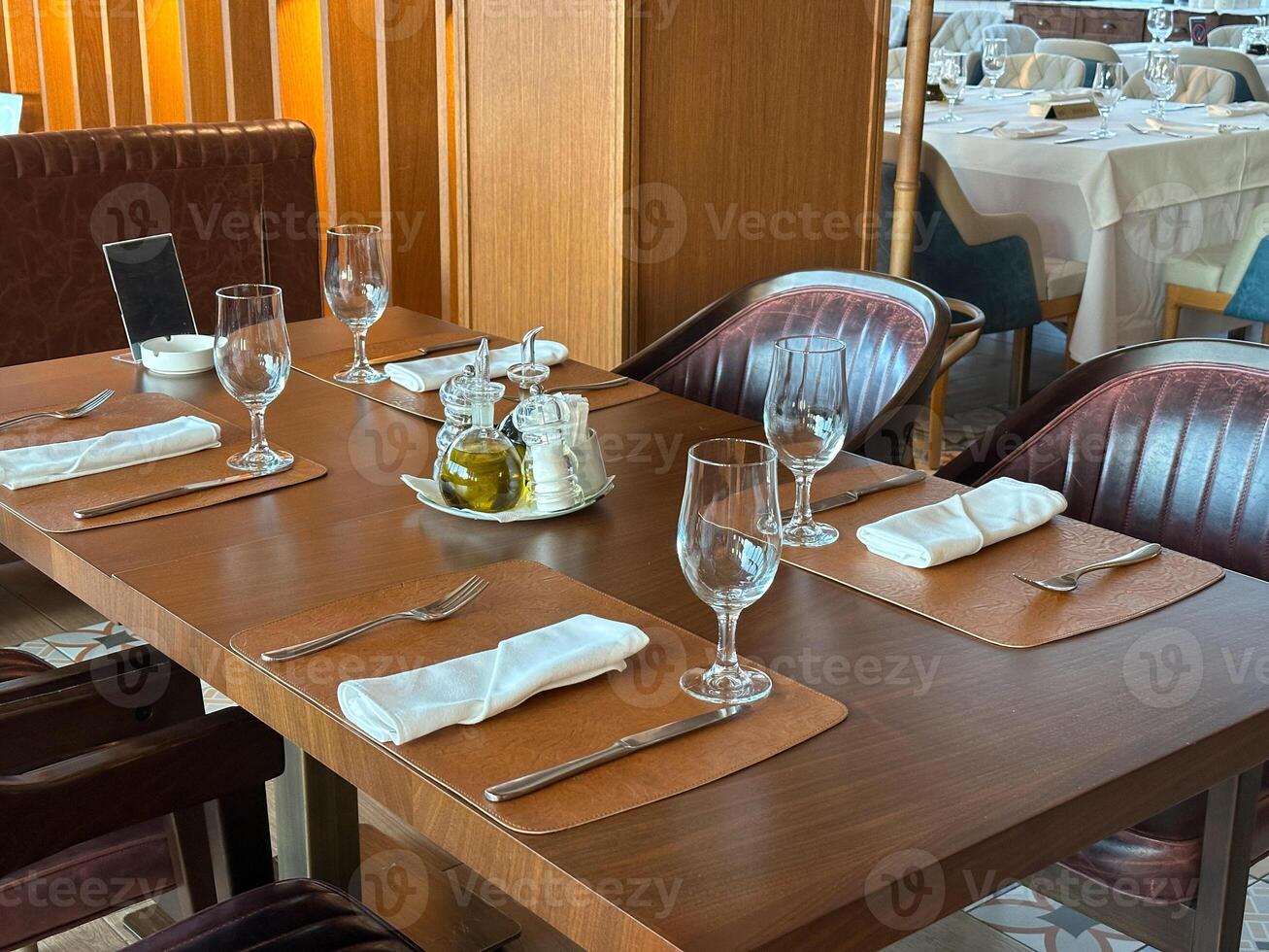 Cozy restaurant interior with elegantly set table, ready for guests. the warmth of the wooden accents and green plants create a welcoming atmosphere. photo