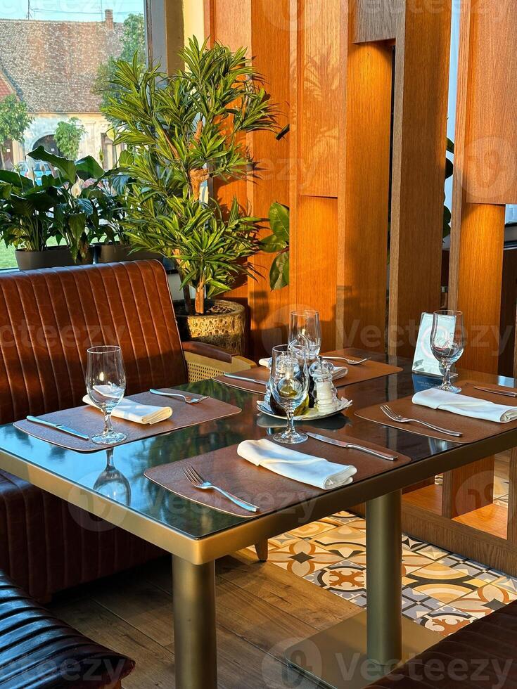Cozy restaurant interior with elegantly set table, ready for guests. the warmth of the wooden accents and green plants create a welcoming atmosphere. photo