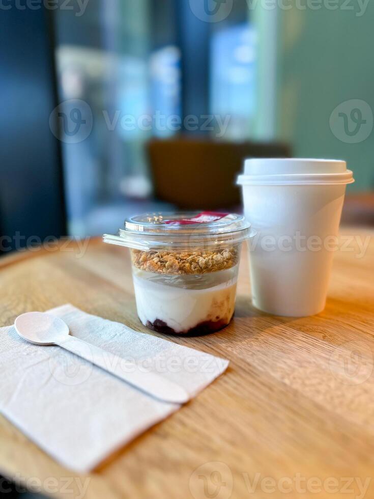 Morning breakfast of yogurt parfait with granola and a hot coffee to go in a cozy cafe setting. Relaxing and inviting atmosphere perfect for breakfast photo