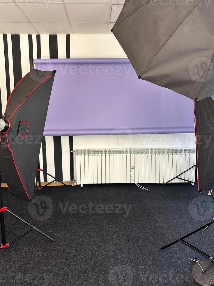 Professional photography studio setup with lighting equipment and a purple backdrop. the studio is well-equipped and ready for a photo session or recording