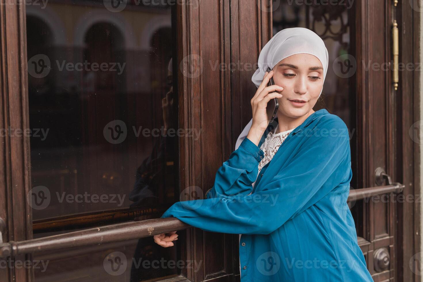 Portrait of young asian muslim student woman talking on the mobile phone outdoors photo