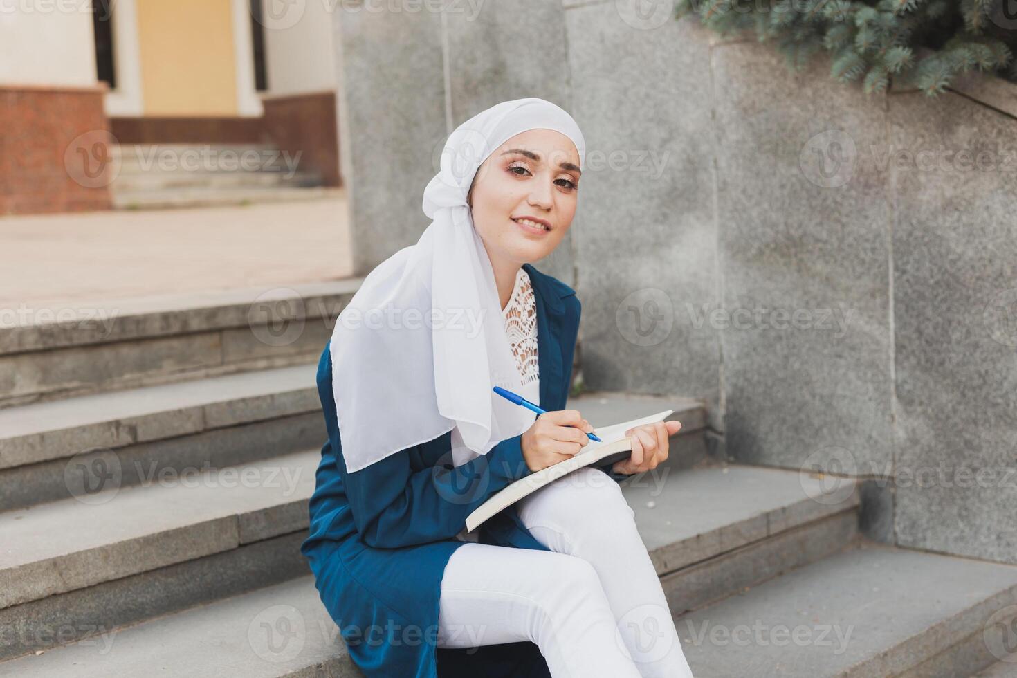 Arab female student sitting on stairs in downtown. photo