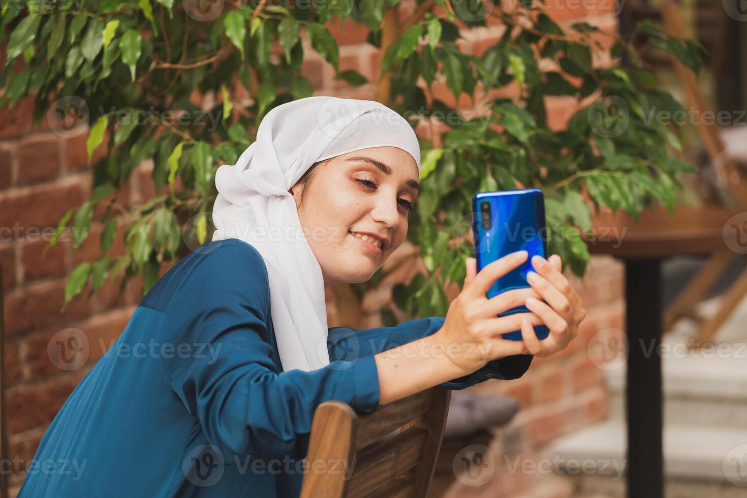 Muslim woman taking selfie. Happy beautiful girl with scarf take picture of her self using smartphone. photo