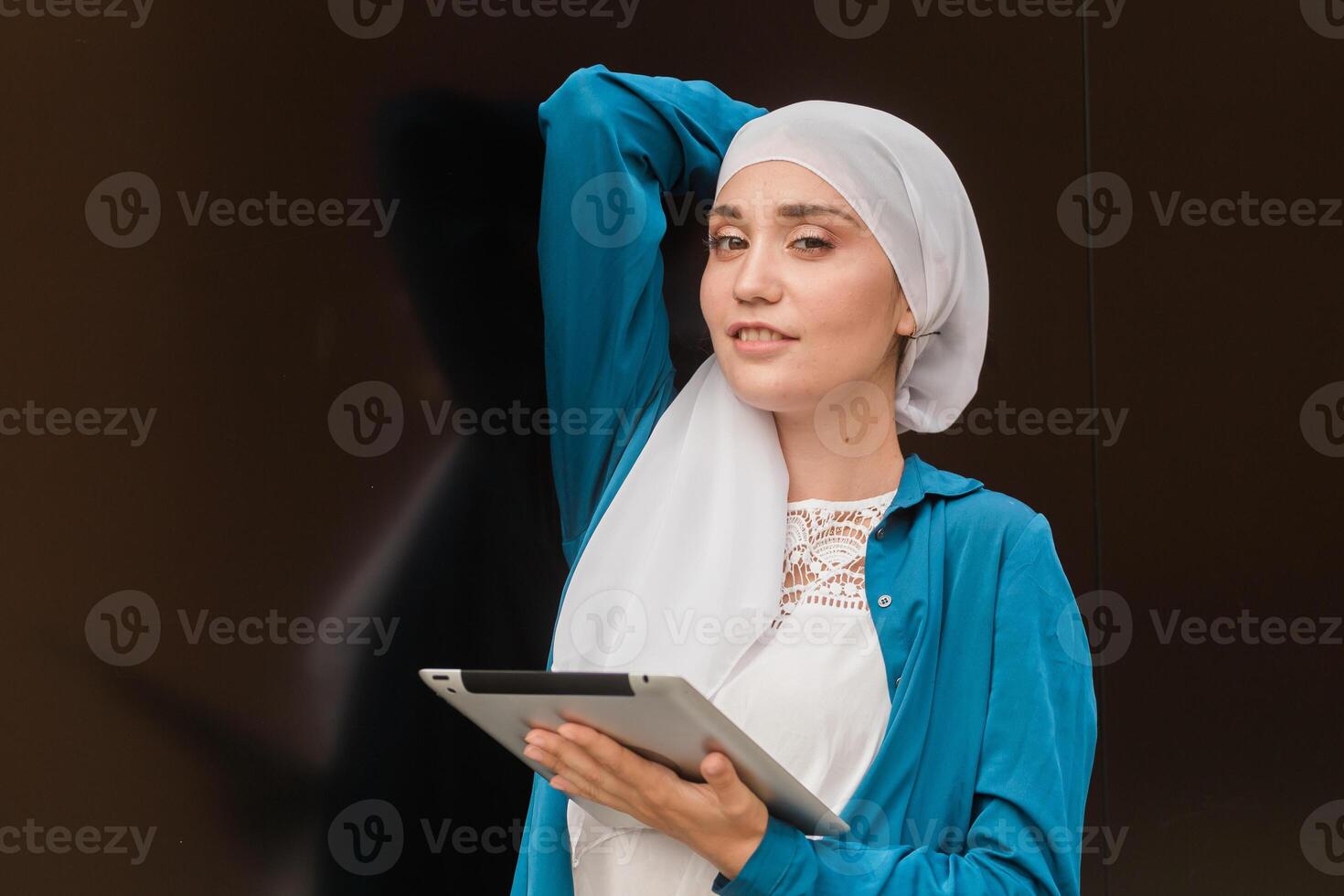 Smiling muslim girl using digital tablet, browsing Internet or social networks outdoor photo