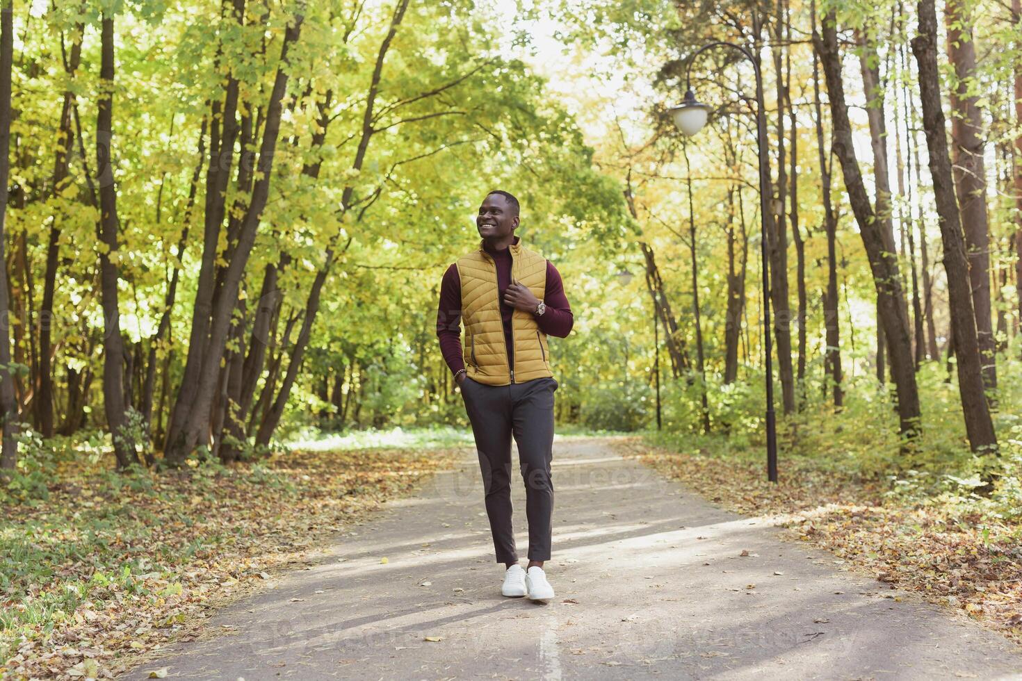 Cheerful young man in stylish clothes walks in autumn park on sunny warm autumn day. Concept of weekend and outdoor recreation photo
