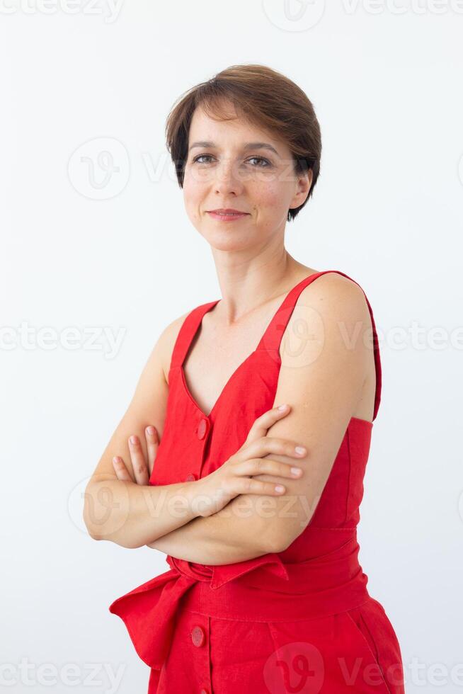 Confident business woman wearing red dress standing with crossed arms. Isolated portrait. photo