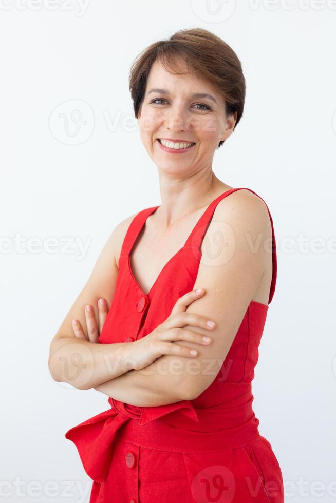 Confident business woman wearing red dress standing with crossed arms. Isolated portrait. photo