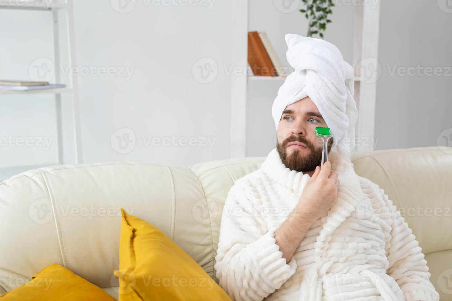 Bearded man with facial massage tool. Male skin care and spa concept. photo