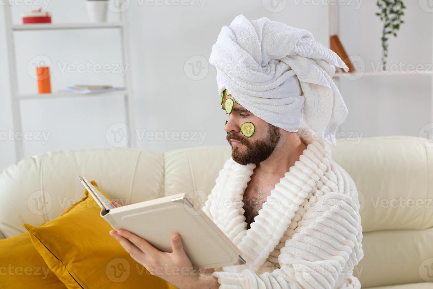 Bearded man enjoys with a cosmetic mask on his face made from slices of cucumber. Men skin care and spa at home concept photo