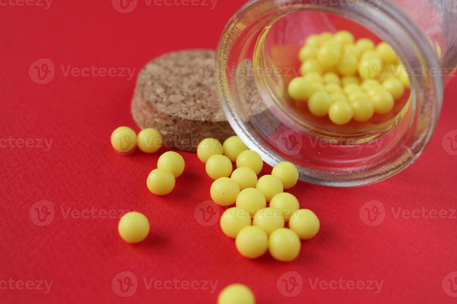 Vitamins homeopathy tablets are sucked out of the packaging jar on a red background with a copyspace close-up photo