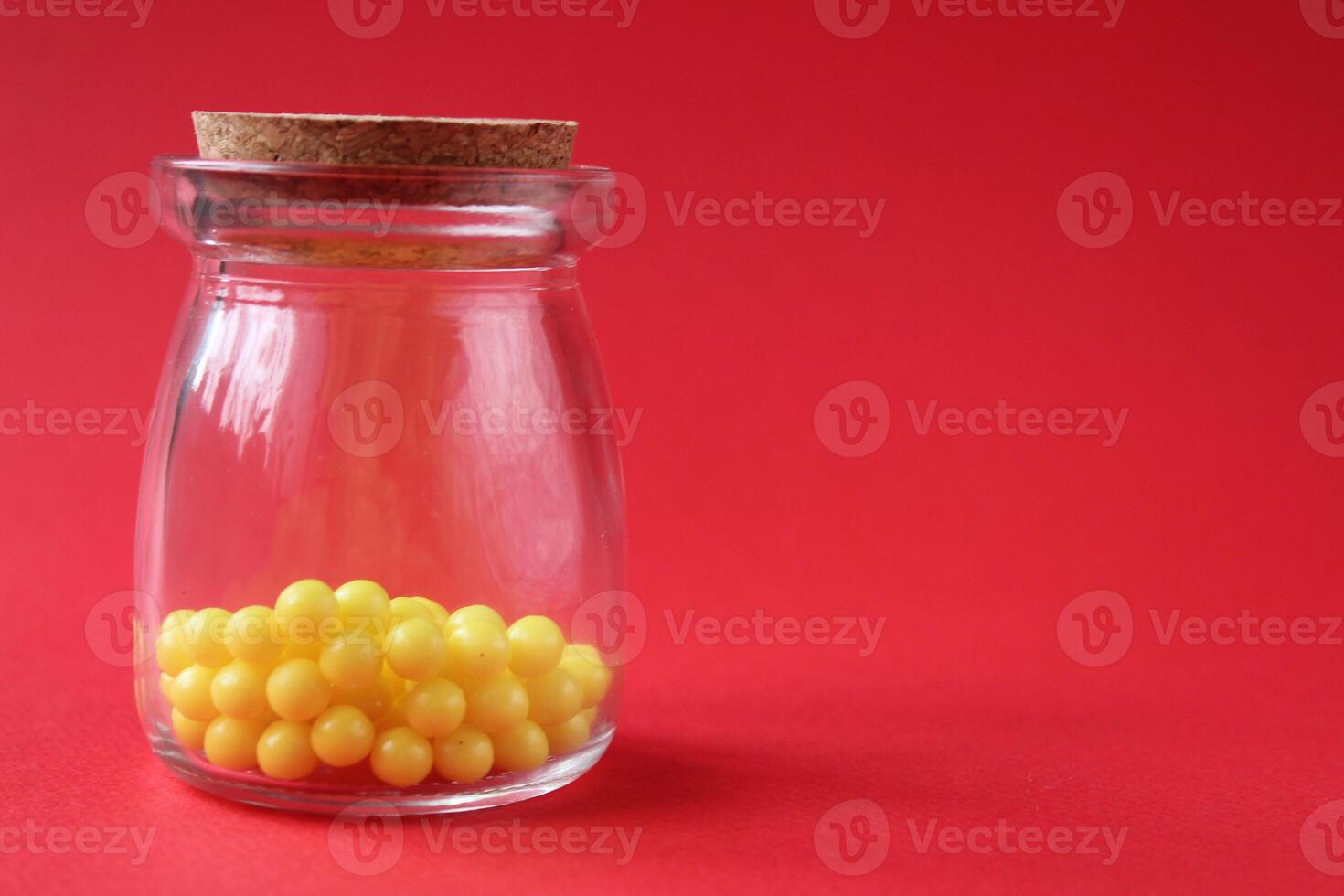 vitamins homeopathy in a glass test tube jar yellow little balls on a red bright background with a place to text copyspace photo
