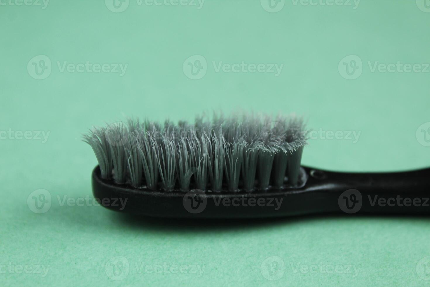 Gray black toothbrush on green background close-up. An old toothbrush photo