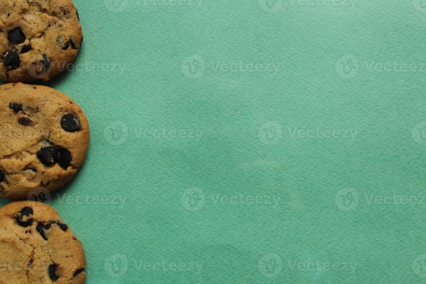 Chocolate chip cookie background on a green background with space for copyspace text. Food background photo