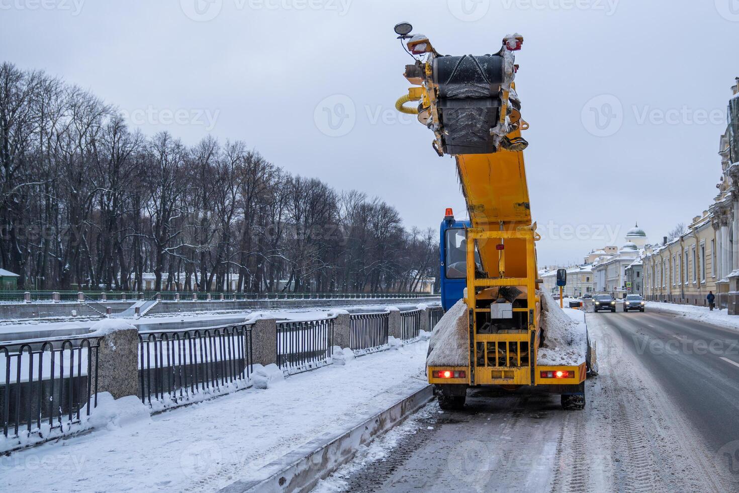 Snowblower truck driving along street, cleaning road, asphalt after snowfall in winter photo