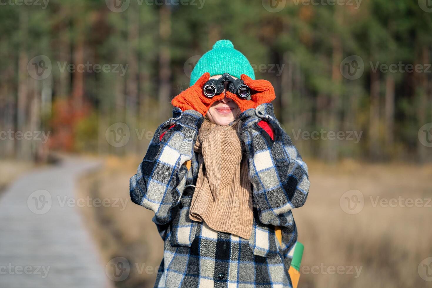 Curious woman with binoculars observe wildlife, landscape in autumn nature park. Environment save photo