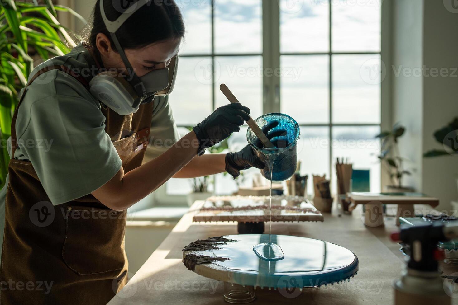Concentrated woman, liquid artist creating pattern on canvas while working with epoxy resin painting photo
