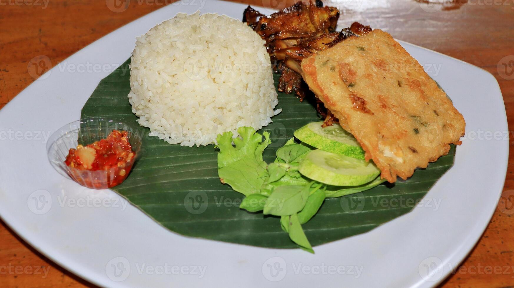 Grilled chicken rice and fried tempeh served on a plate photo