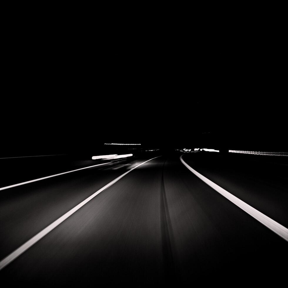 black and white photo of a highway at night