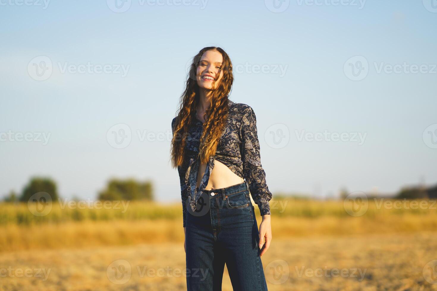 A Joyful Young Woman Smiling Brightly in a Beautiful Sunlit Field Glowing with Light photo