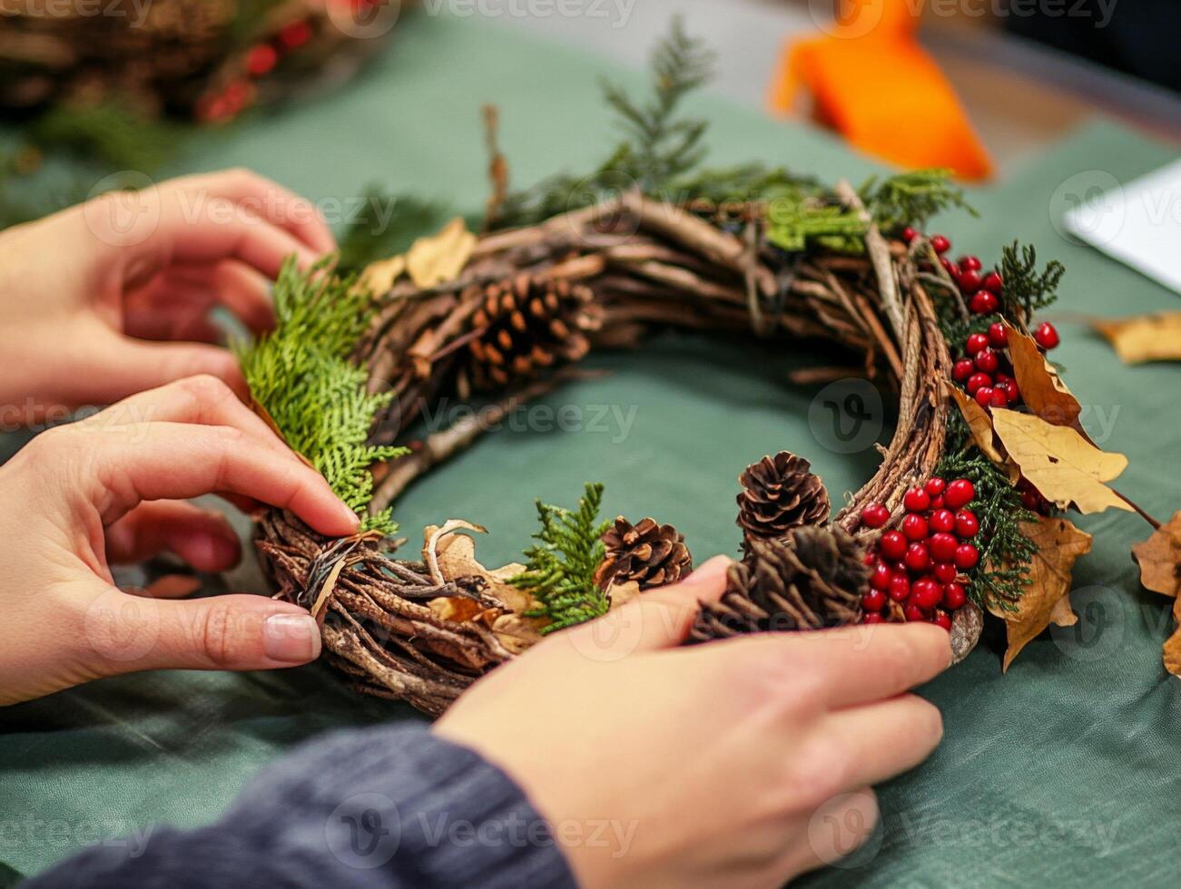 Hands Arranging a Rustic Autumnal Wreath with Pine Cones, Berries, and Twigs photo